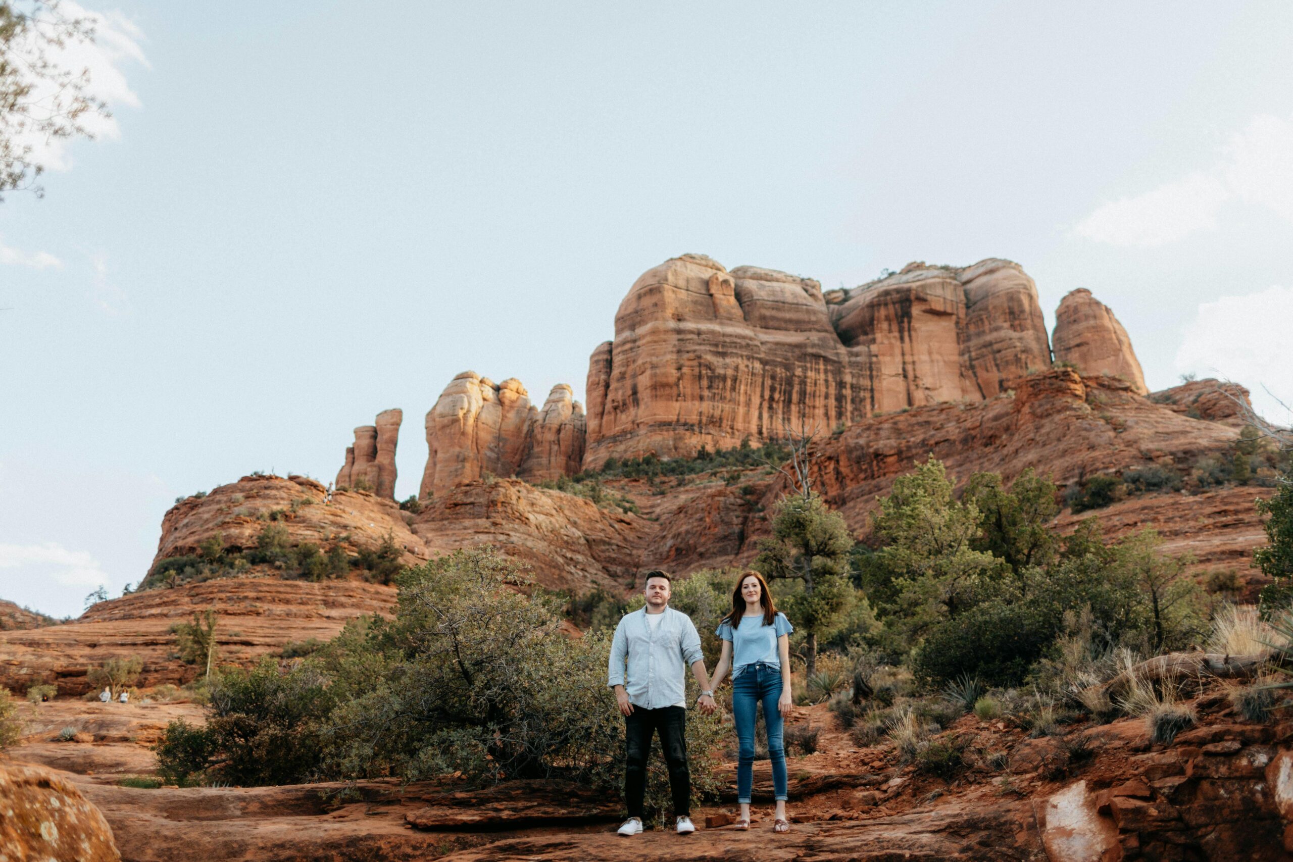 A couple stands in front of the stunning Cathedral Rock in Sedona, Arizona, capturing a serene outdoor moment.